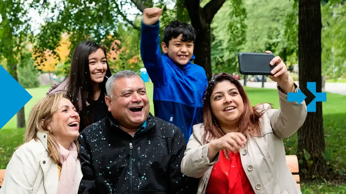 Latin American family enjoying time together outdoors while taking a cheerful group selfie that reflects long distance connection supported by sendvalu.