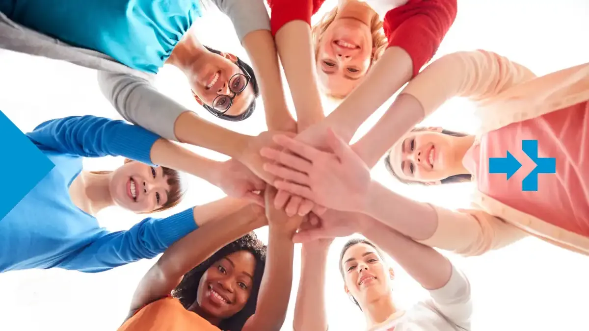 Um grupo diverso de amigos sorridentes formando um círculo com as mãos unidas no centro, simbolizando amizade e conexão global.