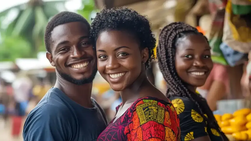 Three friends at a market in Ghana, smiling warmly while enjoying the day together.