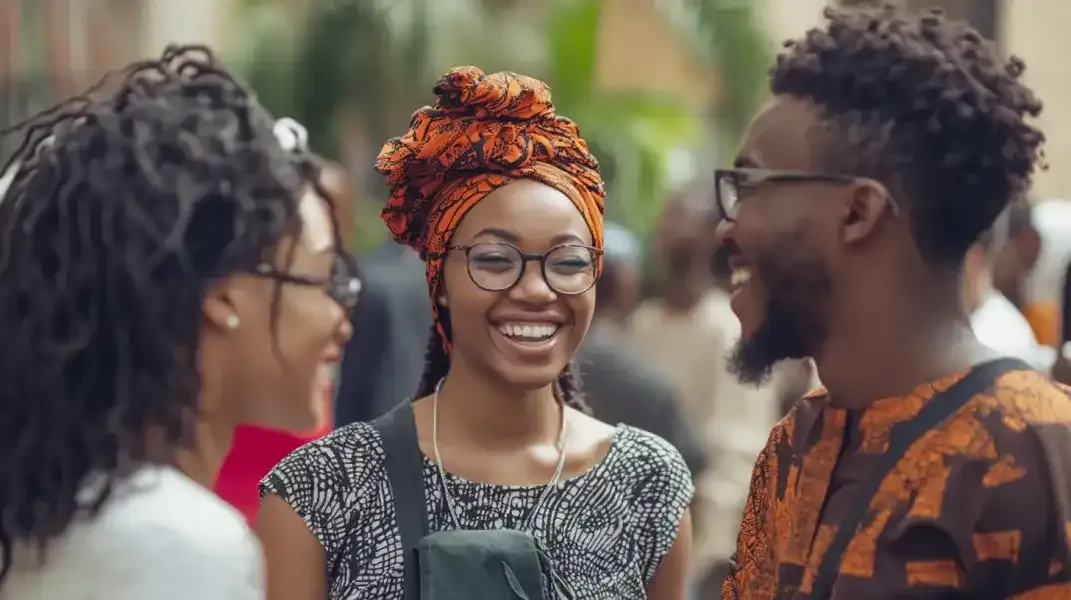 Happy Nigerian friends in conversation, wearing vibrant prints and glasses, symbolizing easy digital communication.