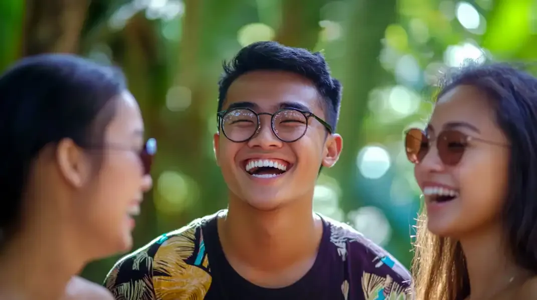 Three Filipino friends sharing a joyful moment outdoors, smiling brightly.