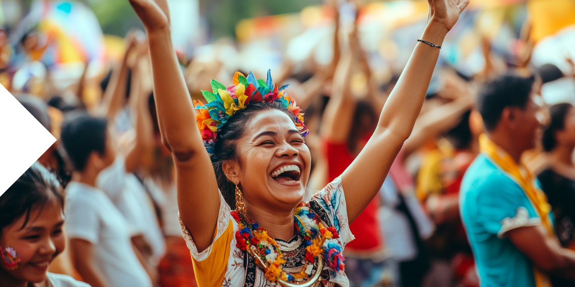 A cheerful woman adorned with vibrant festival decorations celebrates during the Higantes Festival in Angono, Philippines, among a lively crowd