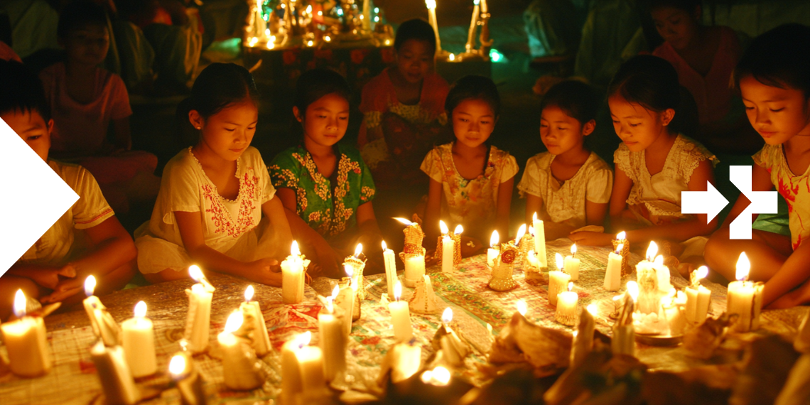 Group of children sitting in a circle, praying together with candles illuminated around them